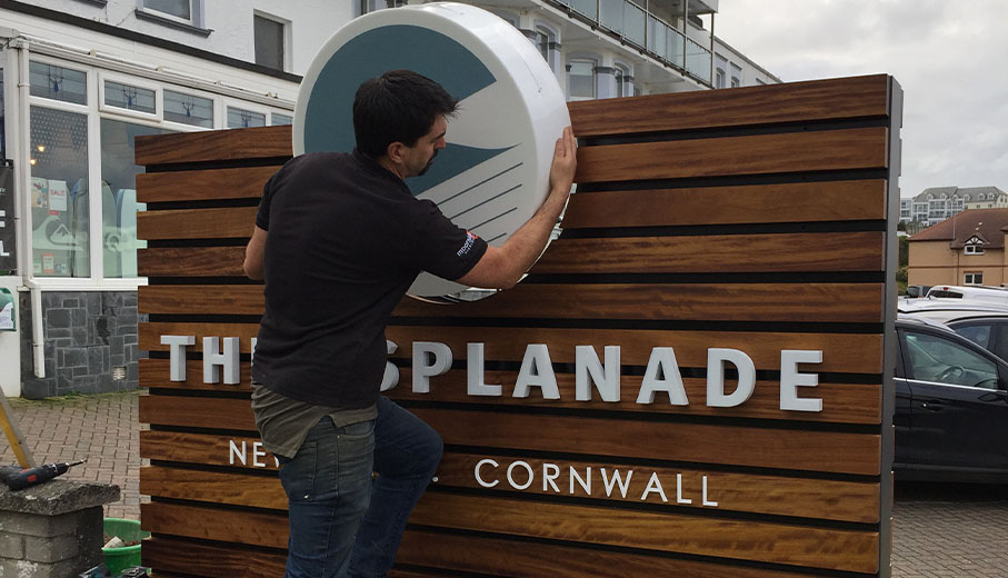 Sign fitter installing 3D acrylic logo into sign in Newquay Cornwall
